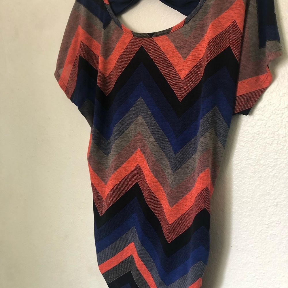 Pullover in geometric pattern, mostly blue and orange, is soft/flowing. Ruching.